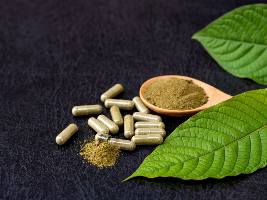 kratom pills and powder with green leaves