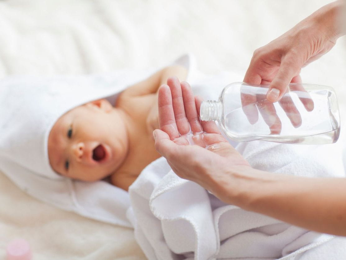 mother pours baby oil onto hand for baby