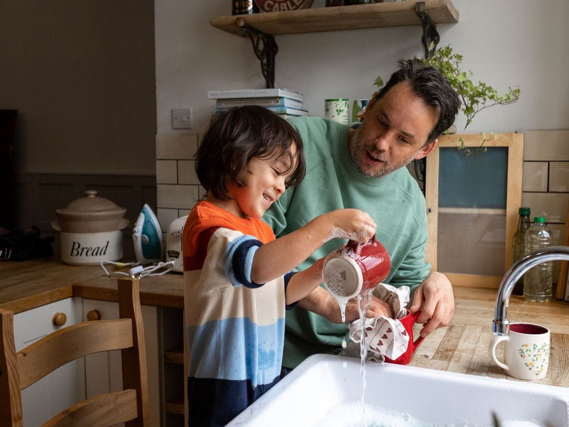 child and father playing with dish soap