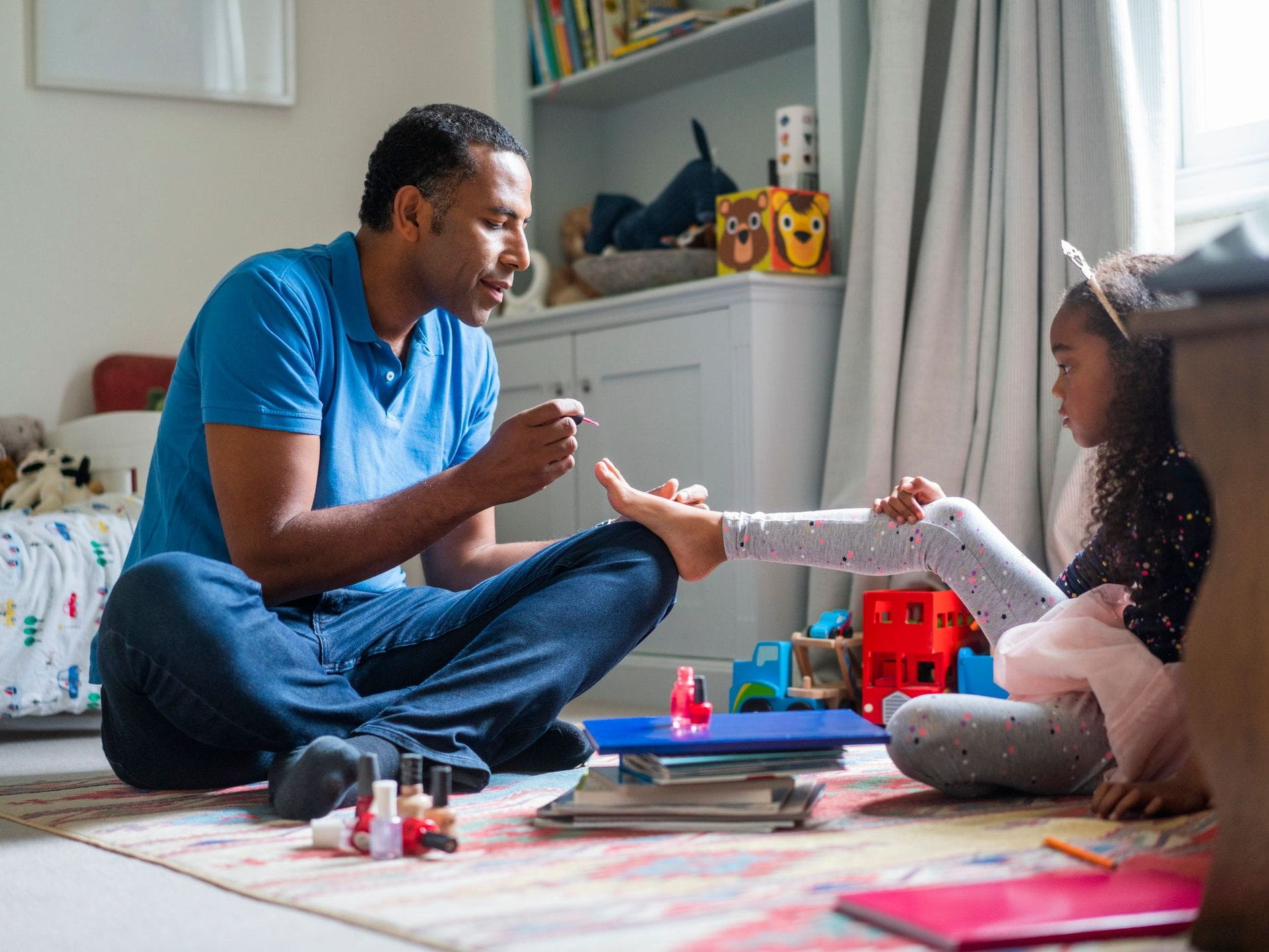 father applies nail polish to daughter's toes