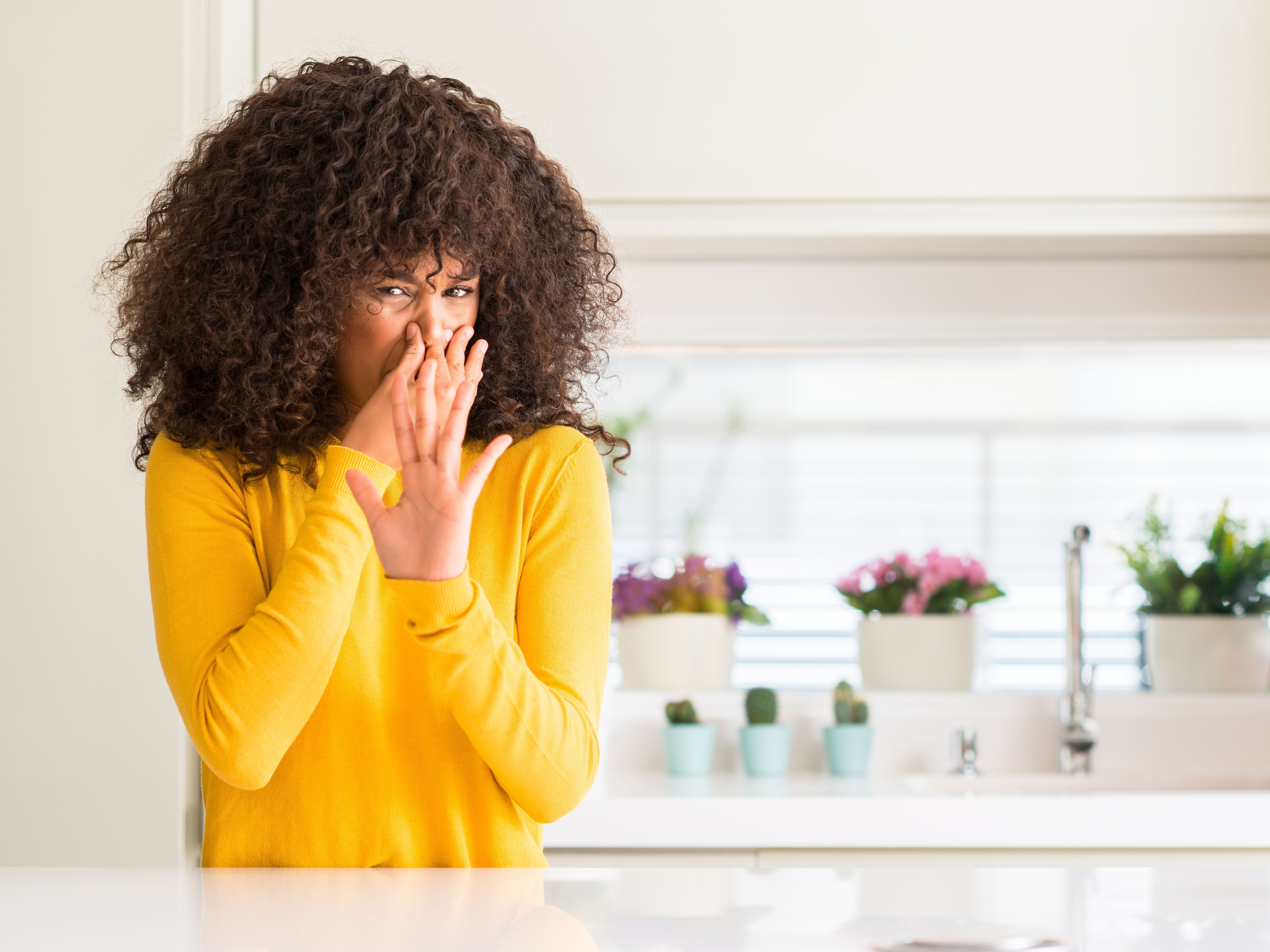 woman holding nose in kitchen