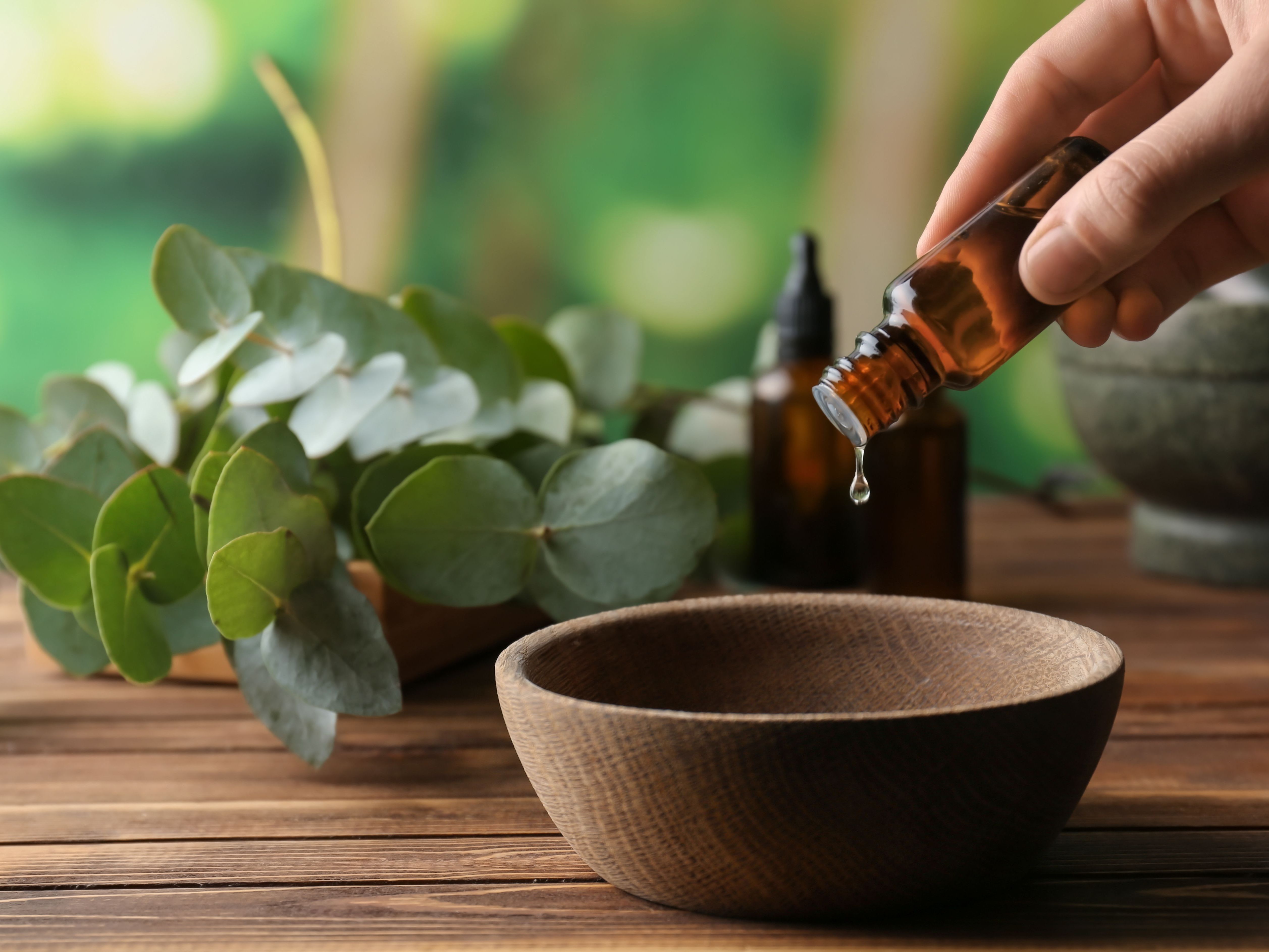 eucalyptus oil being dripped into wooden bowl