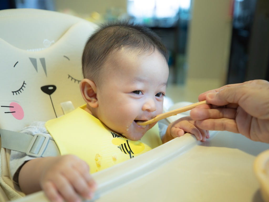 baby being fed with rice cereal