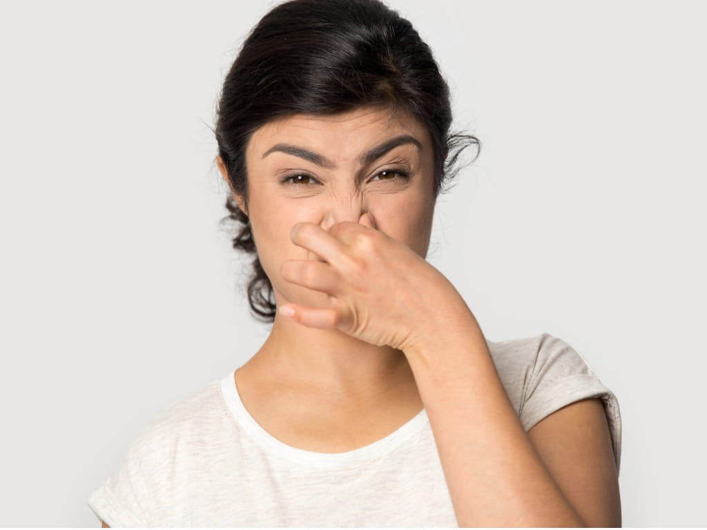 woman holding her nose due to a bad smell