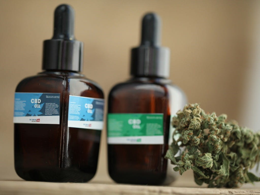 bottles of cbd oil next to dried marijuana