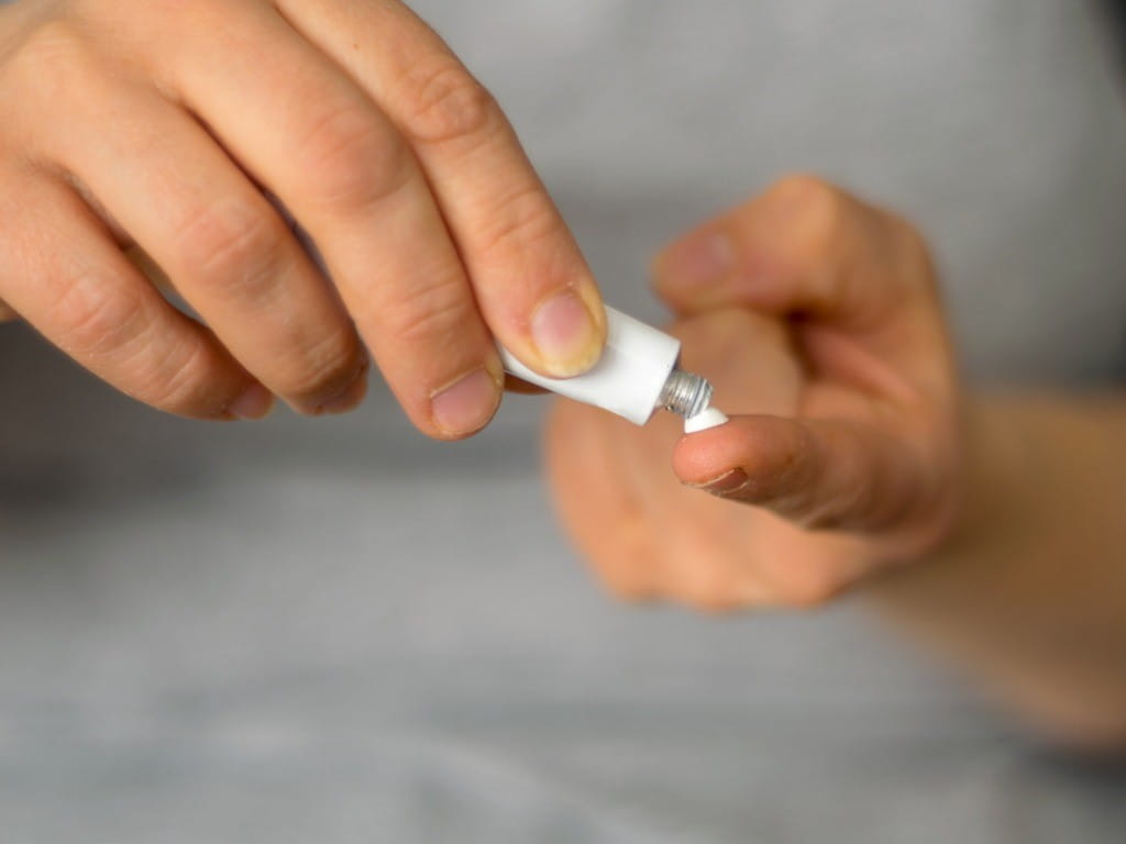 woman squeezes crotamiton scabies ointment onto fingers