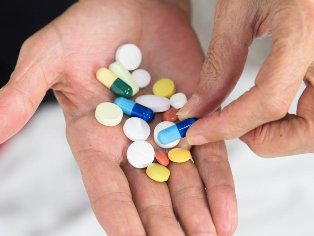 senior woman holding various dementia medications