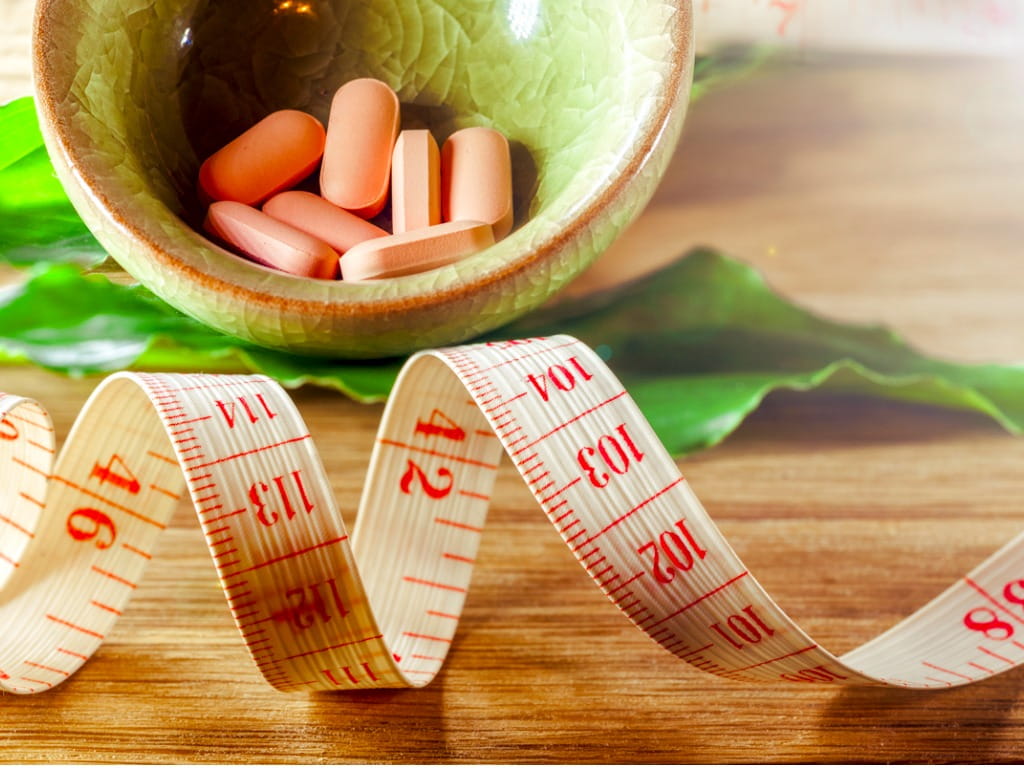 pills next to a measuring tape