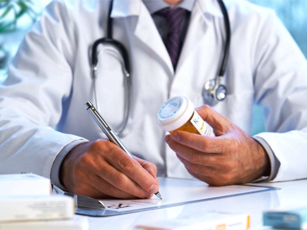doctor writing a prescription and holding a bottom of medication