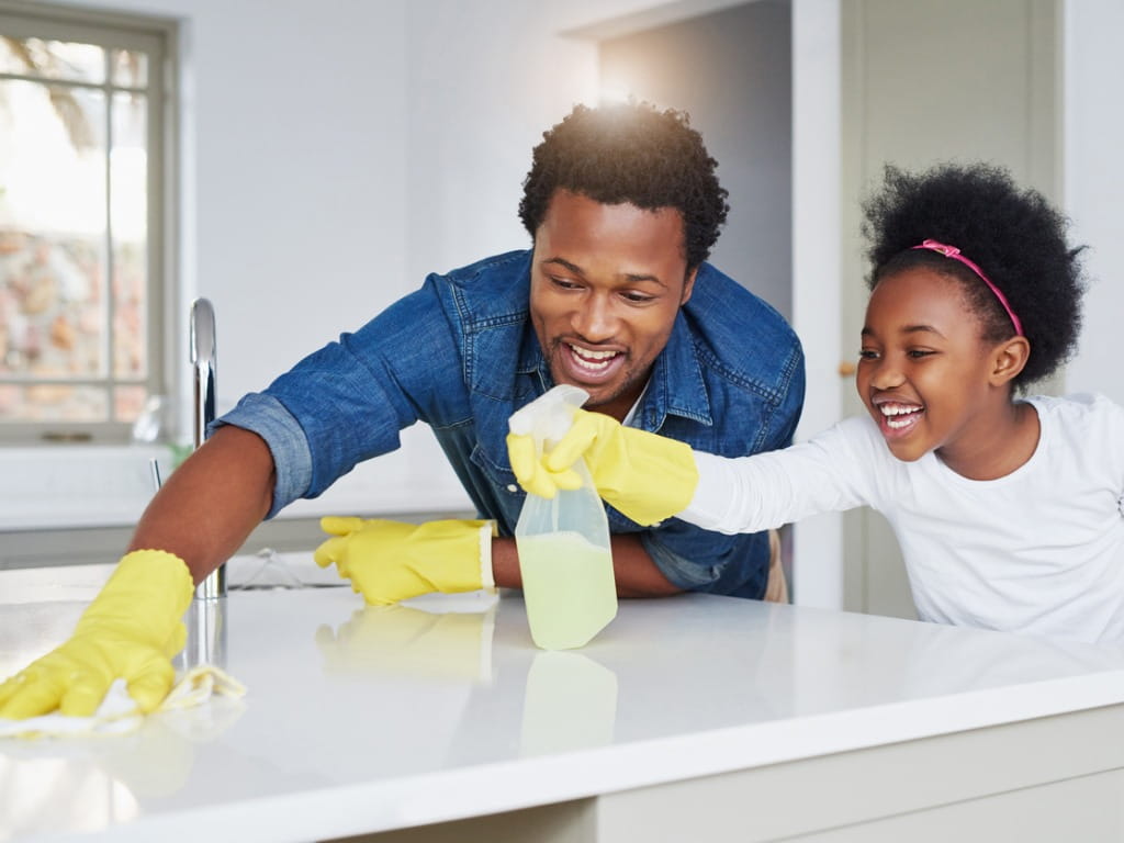 father and daughter cleaning countertop