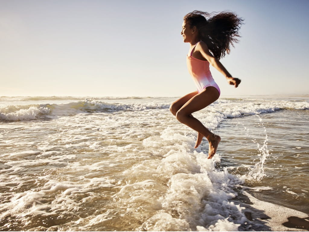 Girl jumping in ocean