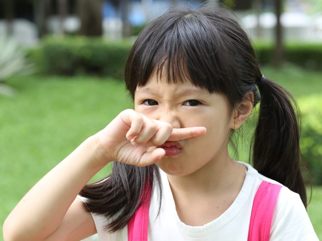 little girl holding her nose due to a bad smell