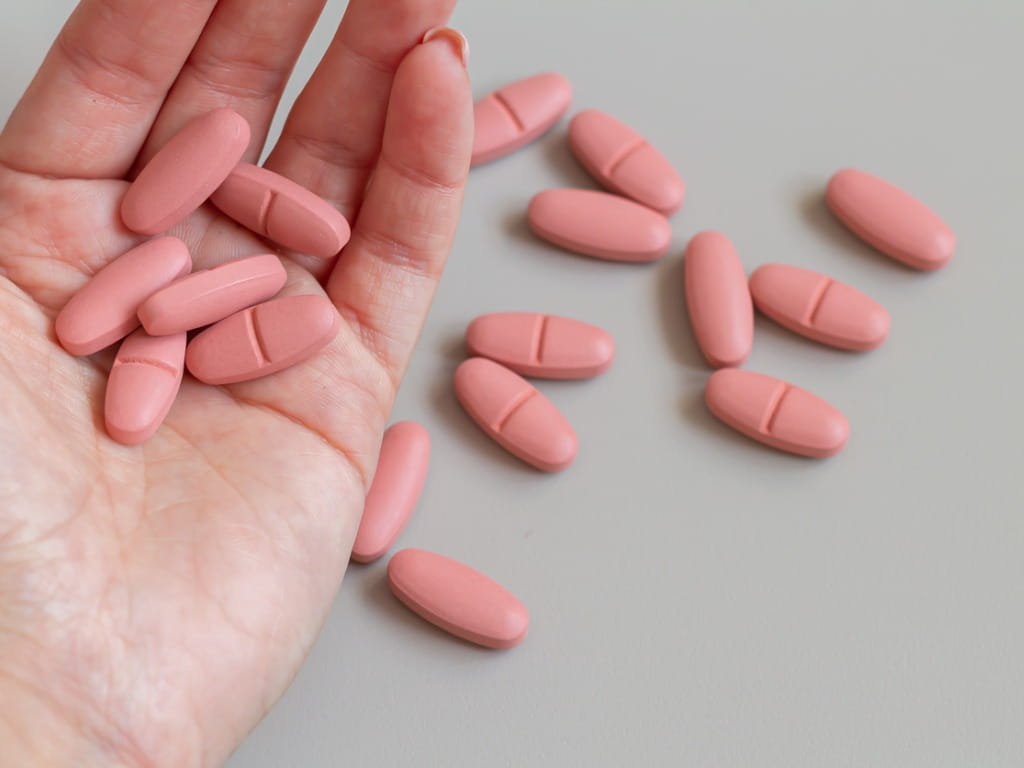 hand holding pink pills