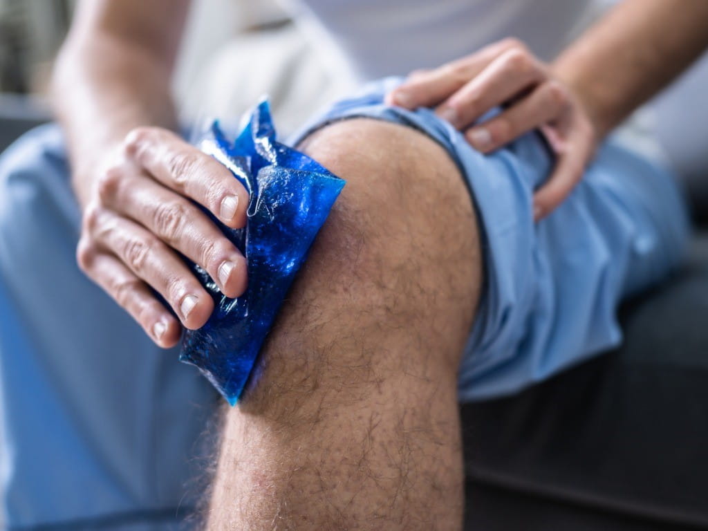 man applying reusable ice pack to knee