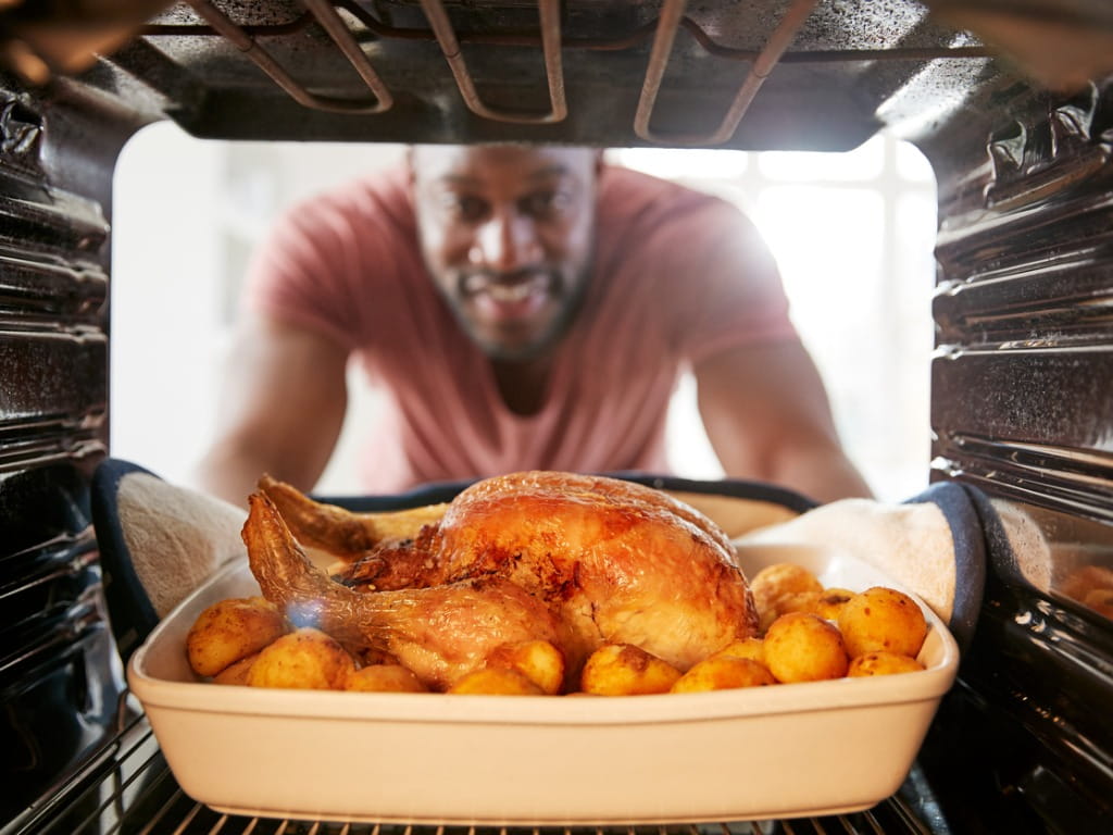 man removing roasted chicken from the oven