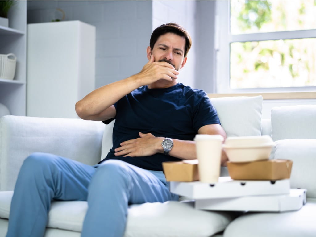 man with heartburn next to empty food containers
