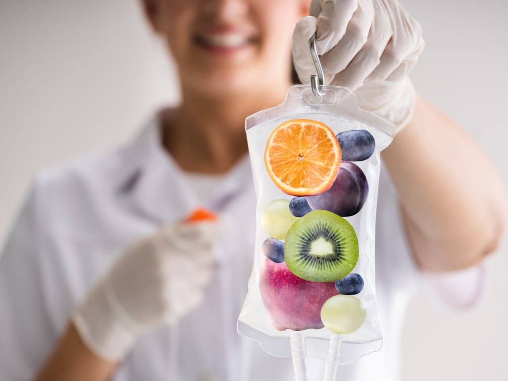 man holding intravenous bag of liquid with fruits inside it