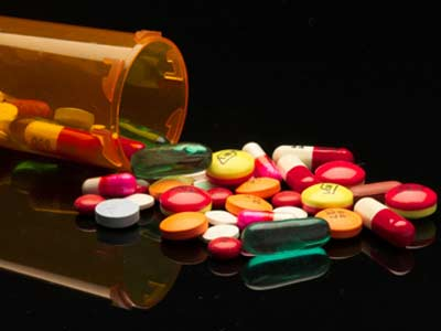 open medication bottle with multicolored pills on the table