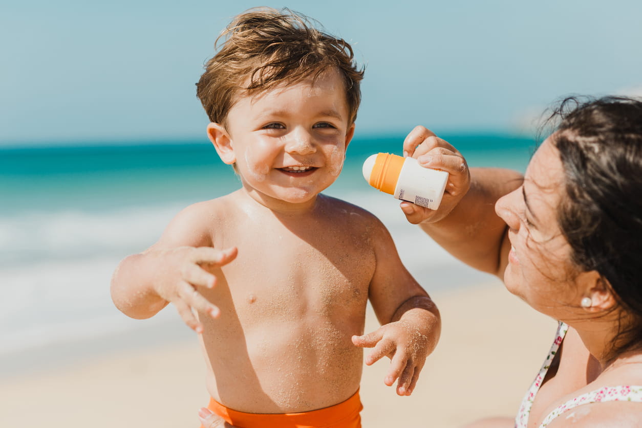 mom applying sunscreen stick to toddler