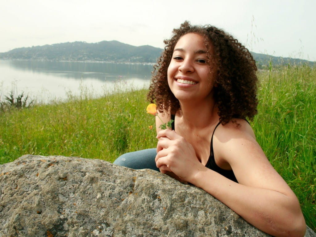 woman holding california poppy while smiling