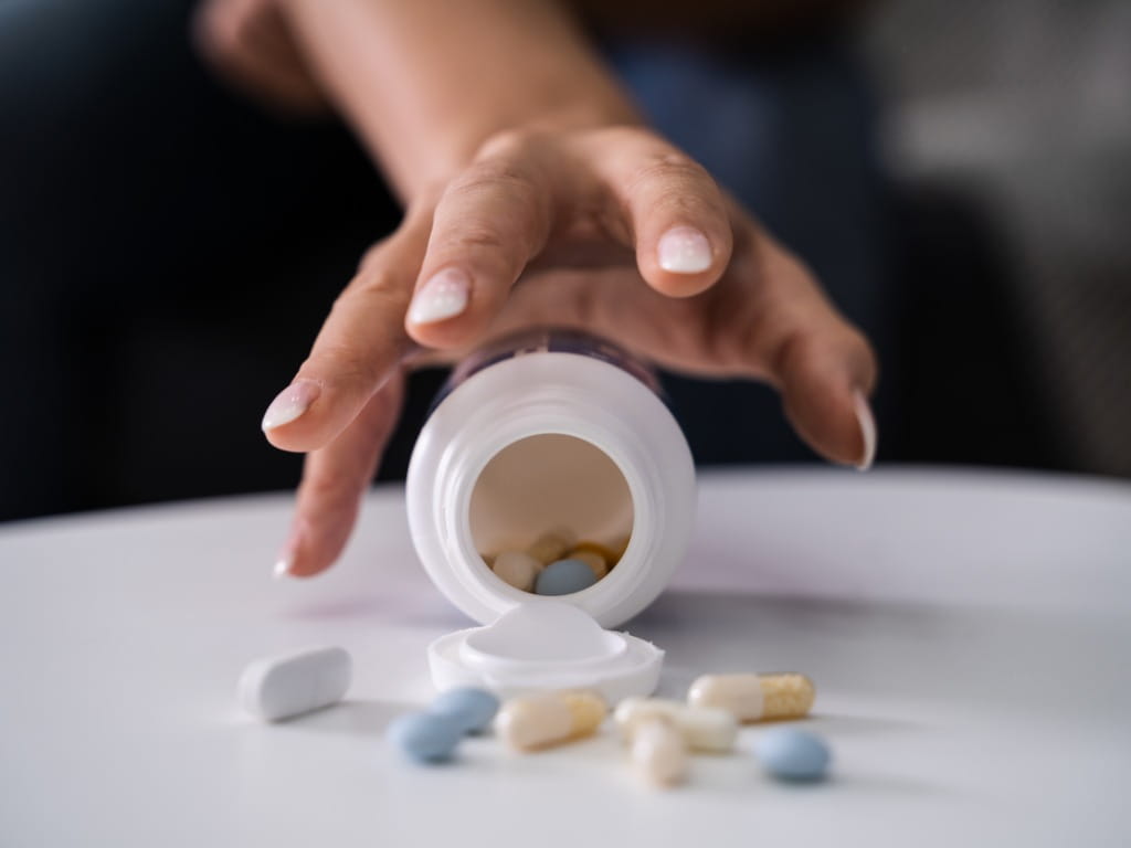 woman's hand reaching for pills