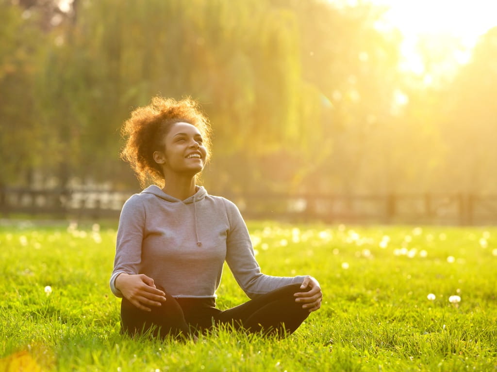 woman sitting outside on the grass smiling at the sun