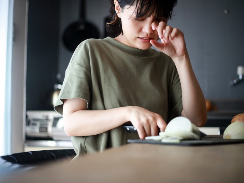 woman's eyes burning while chopping an onion